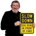 SmartSign – K-9324-AL-12×18 “Slow Down – Dog Runs In Front Of Cars” Sign | 12″ x 18″ Aluminum Black on Yellow